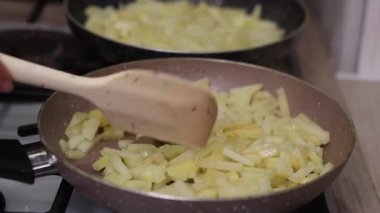 Bir aşçı patates kızartmasını bir spatulayla, iştah açıcı bir dokuya ve sıcak bir mutfak ışığına çevirir..