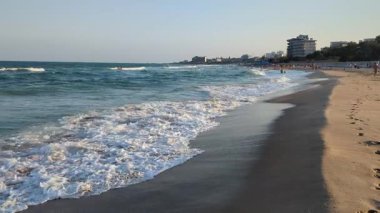 Sıcak ışık, altın kuma doğru hareket eden yumuşak dalgaları vurgular. Huzurlu ve ferahlatıcı bir sahil manzarası yaratır..