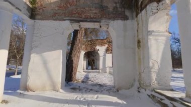 Manzaralı bir kış parkı yürüyüşü berrak güneş ışığı altında başlar ve tarihi sakin bir kar manzarasıyla harmanlayan eski kalıntıların görüntüsüyle sona erer..