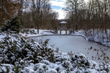Güneşli bir günde karlı bir kış parkı. Parlak güneş ışığı taze karı yansıtır, çıplak ağaçlardan gölgeler bırakır ve sakin, huzurlu ve kıtır kıtır mevsimlik bir atmosfer yaratır..