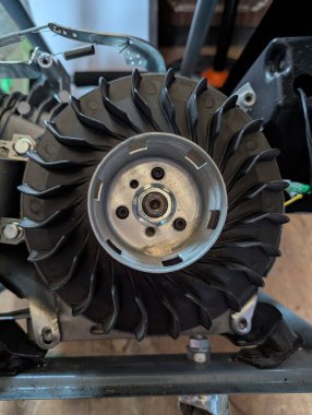 Kapalı küçük motor çark görünür, yıpranmış metal bıçaklar ve merkez fındık, yağ lekeleri, bulanık atölye arka planı, sıcak aydınlatma, odak dışında tamir araçları,