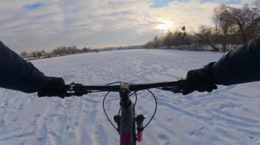 Bisiklet, kışın açık, donmuş bir gölette sürüyor.