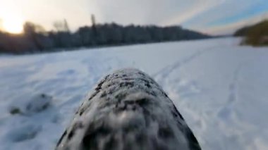 Derin karda hızla ilerleyen bir dağ bisikletinin alçak açılı yakın çekimi. Lastik, kış döngüsünün heyecanını ve enerjisini yakalayarak her yöne doğru tüylü kar sıçramaları yaratıyor..