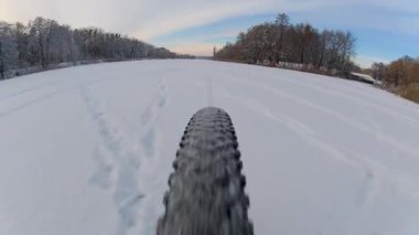 Bir dağ bisikletinin arka tekerinin alçak açılı yakın çekimi derin karda hızla ilerliyor. Lastik, kış döngüsünün heyecanını ve enerjisini yakalayarak her yöne doğru tüylü kar sıçramaları yaratıyor..