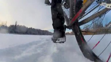 Kışın donmuş bir gölde bisikletçinin dinamik taban üstü çekimi. Odaklandığımız nokta buzla temas eden lastikler. Kar parkının soğuk ve el değmemiş ortamını gösteriyor..