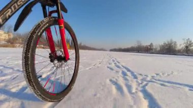 Kış macerası: Bir bisiklet tekerleği donmuş bir göl boyunca hareket ediyor, aşağıdan manzara.