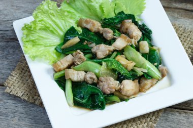 Kale ve yan domuz kızarmış istiridye soslu beyaz plaka üzerinde