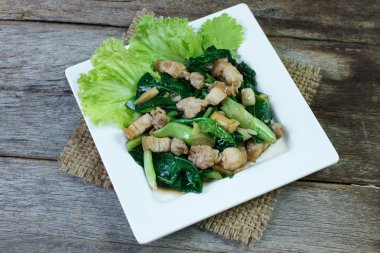 Kale ve yan domuz kızarmış istiridye soslu beyaz plaka üzerinde