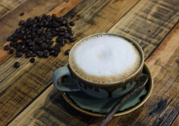 Kapuçino ahşap arka plan üzerinde kahve bir fincan