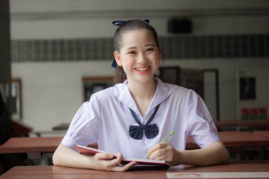 Asya thai ortaokul üniforması güzel kız bir kitap okudu.