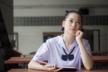 Asya thai ortaokul üniforması güzel kız bir kitap okudu.