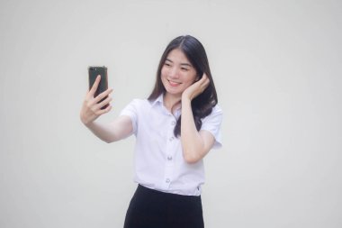 Yetişkin öğrenci üniforması güzel kız akıllı telefonuyla selfie çekiyor.