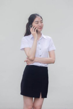 Yetişkin öğrenci üniforması. Güzel bir kız, akıllı telefondan arıyor.