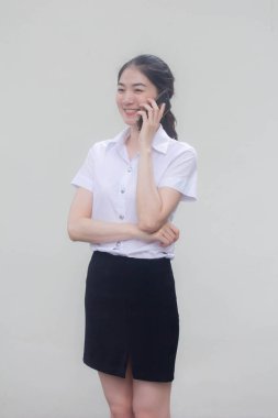 Yetişkin öğrenci üniforması. Güzel bir kız, akıllı telefondan arıyor.