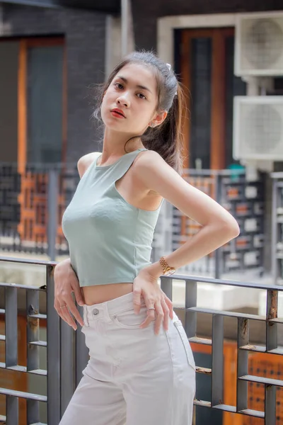 タイの肖像中国大人の美しい女の子緑のシャツ白いジーンズリラックスして笑顔 — ストック写真
