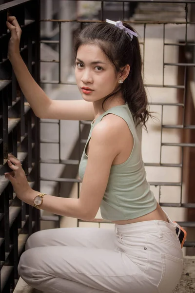 泰国人的画像中国成年人漂亮的女孩绿色衬衫白色牛仔裤放松微笑 — 图库照片