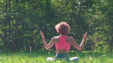 Aktif bir kadın şehir parkında çimlerin üzerinde yoga yapıyor. Sağlıklı yaşam tarzı kavramı, yaz parkında egzersiz, açık havada egzersiz..