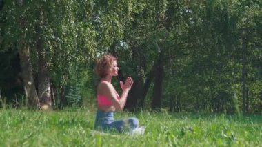 Aktif bir kadın şehir parkında çimlerin üzerinde yoga yapıyor. Sağlıklı yaşam tarzı kavramı, yaz parkında egzersiz, açık havada egzersiz..