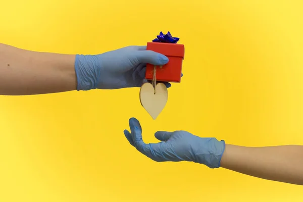 Eldivenli eller, Sevgililer Günü 'nde sarı arka planda kalbi olan bir hediye verir ve kabul eder..