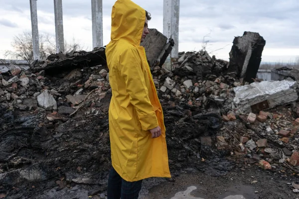 黄色の防護服を着た男が破壊された建物の中に立っている 人間が災害を起こし 燃え盛る炎の後 — ストック写真