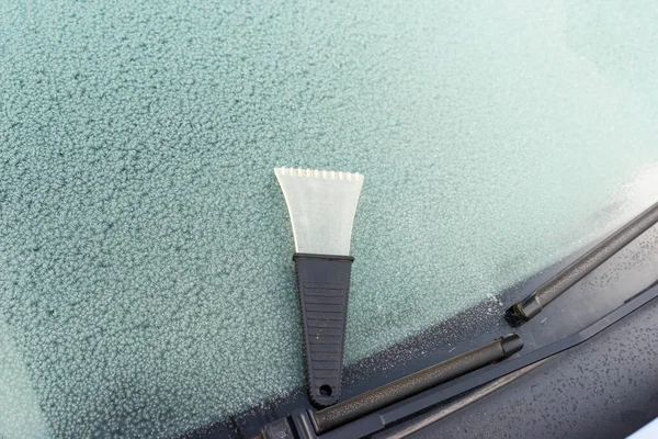 frosted car glass. Frosty patterns on a car windscreen . scraper for cleaning glass from ice