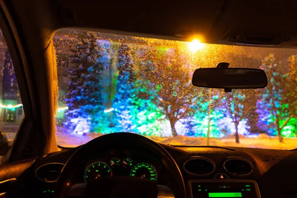 frosted car glass. snow covered car windshield. view from inside the car on the night city