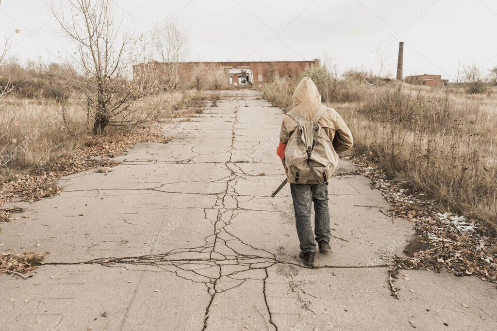 wandering boy. boy with a gun. boy goes to an abandoned building. boy stands in front of a building. Post apocalypse. Boy traveling on foot in a post-apocalyptic world in search of food.