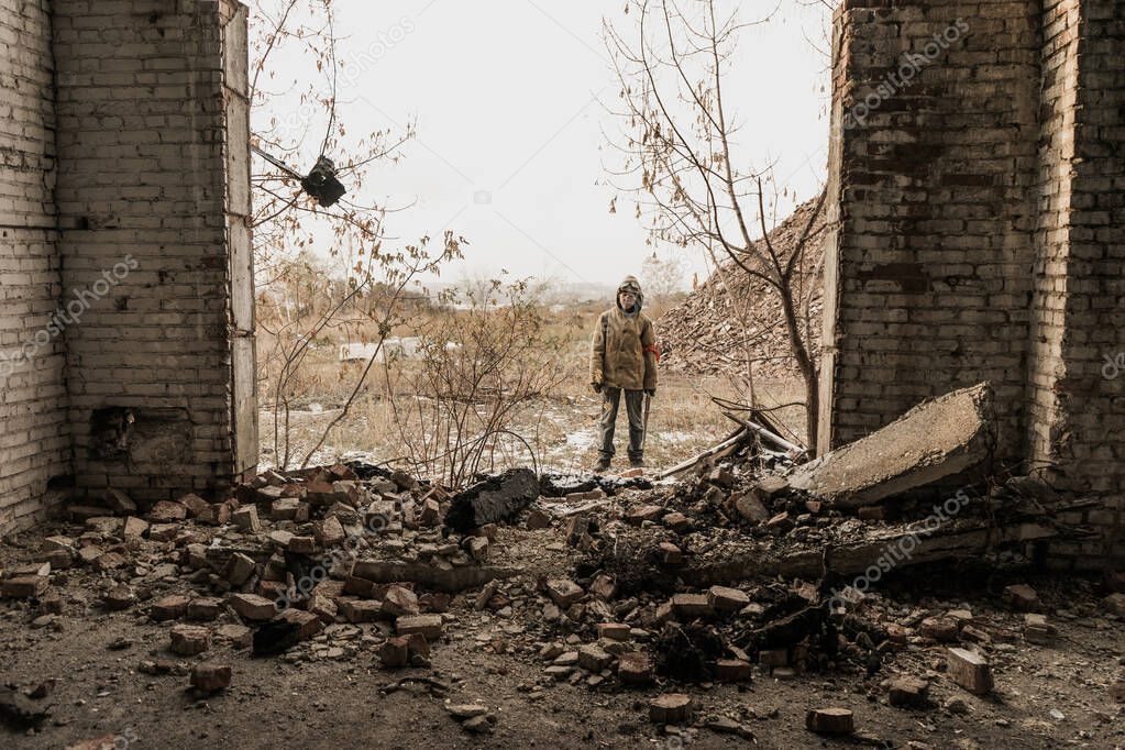 wandering boy. boy with a gun. boy goes to an abandoned building. boy stands in front of a building. Post apocalypse. Boy traveling on foot in a post-apocalyptic world in search of food.