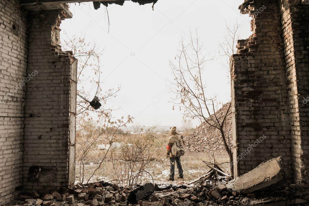 wandering boy. boy with a gun. boy goes to an abandoned building. boy stands in front of a building. Post apocalypse. Boy traveling on foot in a post-apocalyptic world in search of food.
