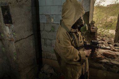 Çocuk elinde bir silahla ayakta duruyor. Gaz maskeli çocuk..