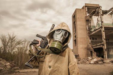 Çocuk elinde bir silahla ayakta duruyor. Gaz maskeli çocuk..