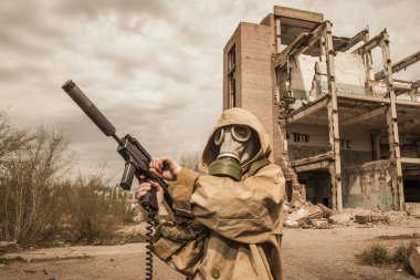 Çocuk elinde bir silahla ayakta duruyor. Gaz maskeli çocuk..