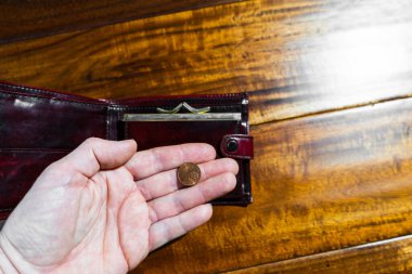 Bir yetişkinin eli avucunun içinde sentleri tutar ve cüzdanını açar..