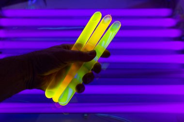 Ultraviyole ışığın altında flüoresein şişede parlıyor. Elinde floresan sıvısı tutan bir adamın yakın çekimi..