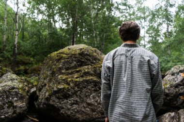 Genç adam ormanda duruyor. Arkadan bak..