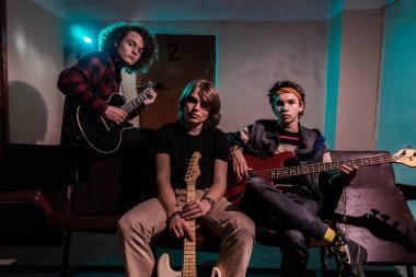 Müzik ve moda. Müzisyenlerin grup fotoğrafı. Müzik aletleri tutan yakışıklı genç adamlar..