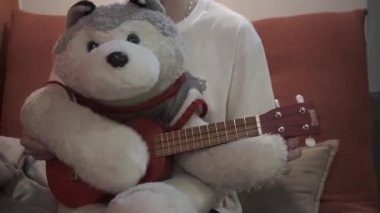 Genç adam yumuşak bir oyuncak ayıyla oynuyor. Kukla ayı gitar çalıyor..