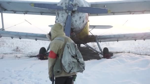 小男孩慢慢走向滑翔机 世界末日之后的世界 核冬天 被遗弃的飞机 一个拿着枪的男孩 穿着有帽檐的防护斗篷的青少年 启示录 — 图库视频影像