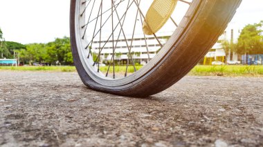 Akşamları otoparkta arka lastiği patlamış ve teknisyenin tamir etmesini bekleyen eski model bir bisiklet. Renkleri ve mercekleri büyüt. 