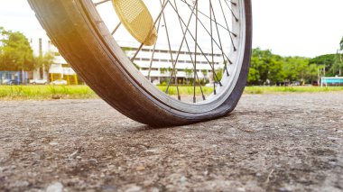 Akşamları otoparkta arka lastiği patlamış ve teknisyenin tamir etmesini bekleyen eski model bir bisiklet. Renkleri ve mercekleri büyüt. 