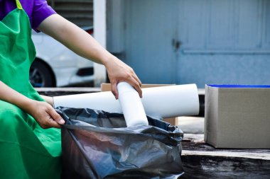 Beyaz plastik konteynırları siyah plastik torbaya yerleştiriyor.