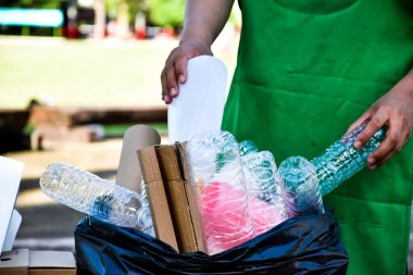 Beyaz, plastik kapları elleriyle siyah poşetlere ayırıyor.