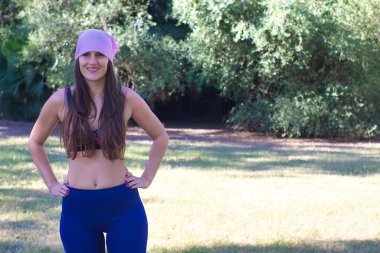 Pembe başörtüsüyle parkta yoga dersi alan bir kadın.