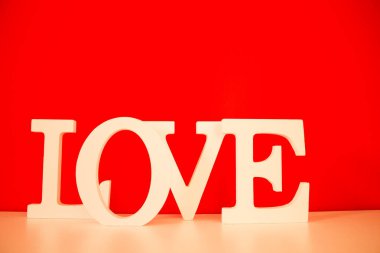 Kırmızı arkaplanlı beyaz aşk kelimesi.
