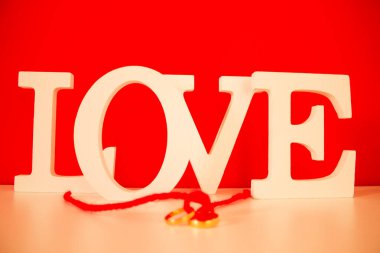 Aşk sözcüğü kırmızı arka planda aşk ve sarı yüzükler