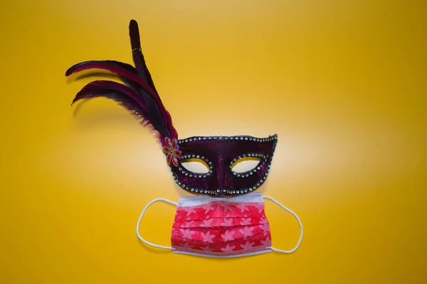 purple carnival mask with sanitary mask on a yellow background