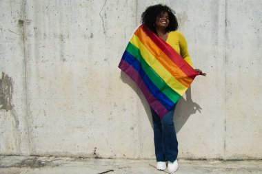 Çok mutlu bir Afro-Amerikan lezbiyen kadın. Gri bir arka planda eşcinsel gururu var.