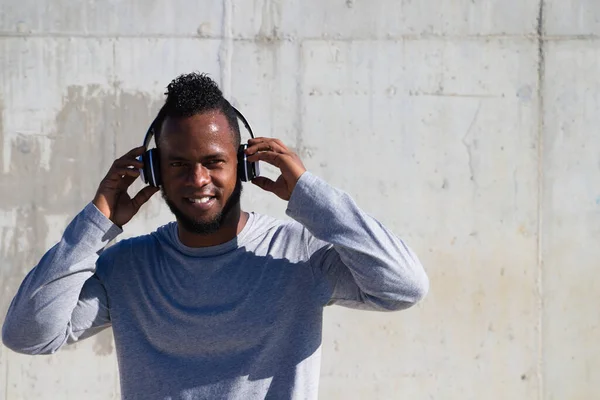 African-american man listening to music with white headphones. The man is happy because he likes music very much