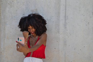 Güzel afro-amerikalı kadın video konuşmasında çok mutlu. Kadın kırmızı bir üst giyiyor. Video çağrısı kavramı.