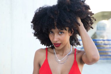 Güzel Afro-Amerikan kadın gülümseyen ve kameraya bakan farklı pozlar veren ve yüzüyle jestler yapan. Kadın kırmızı bir üst ve kırmızı bir ruj sürüyor. Mutluluk kavramı